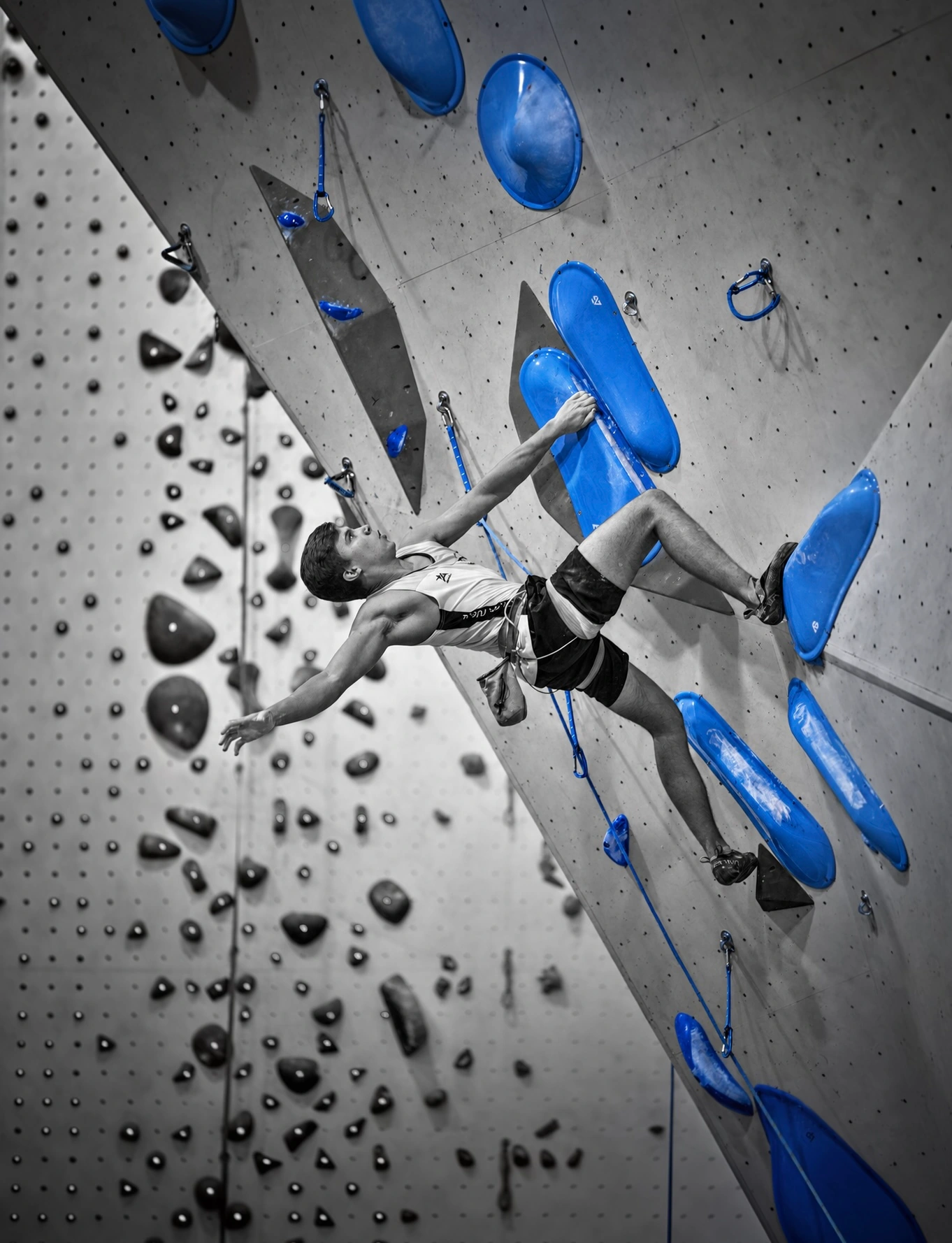 Climber reaching across an indoor wall with blue holds